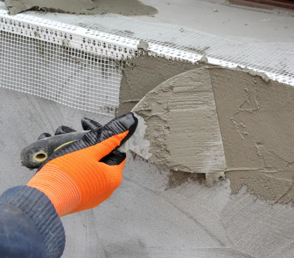 Worker spreading mortar over styrofoam insulation with trowel
